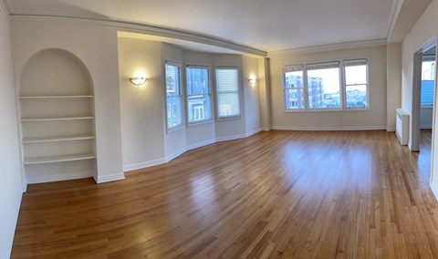 an empty living room with a hard wood floor and white walls