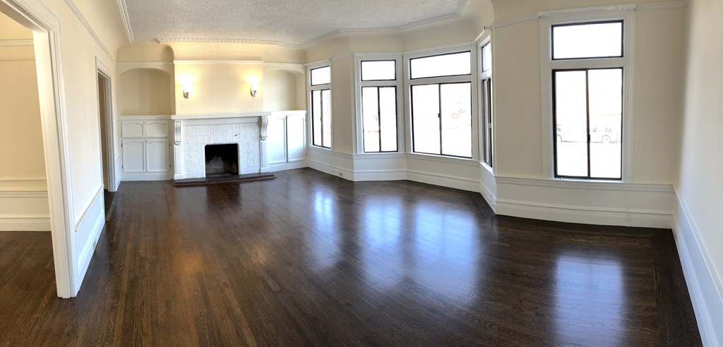 an empty living room with wood floors and a fireplace
