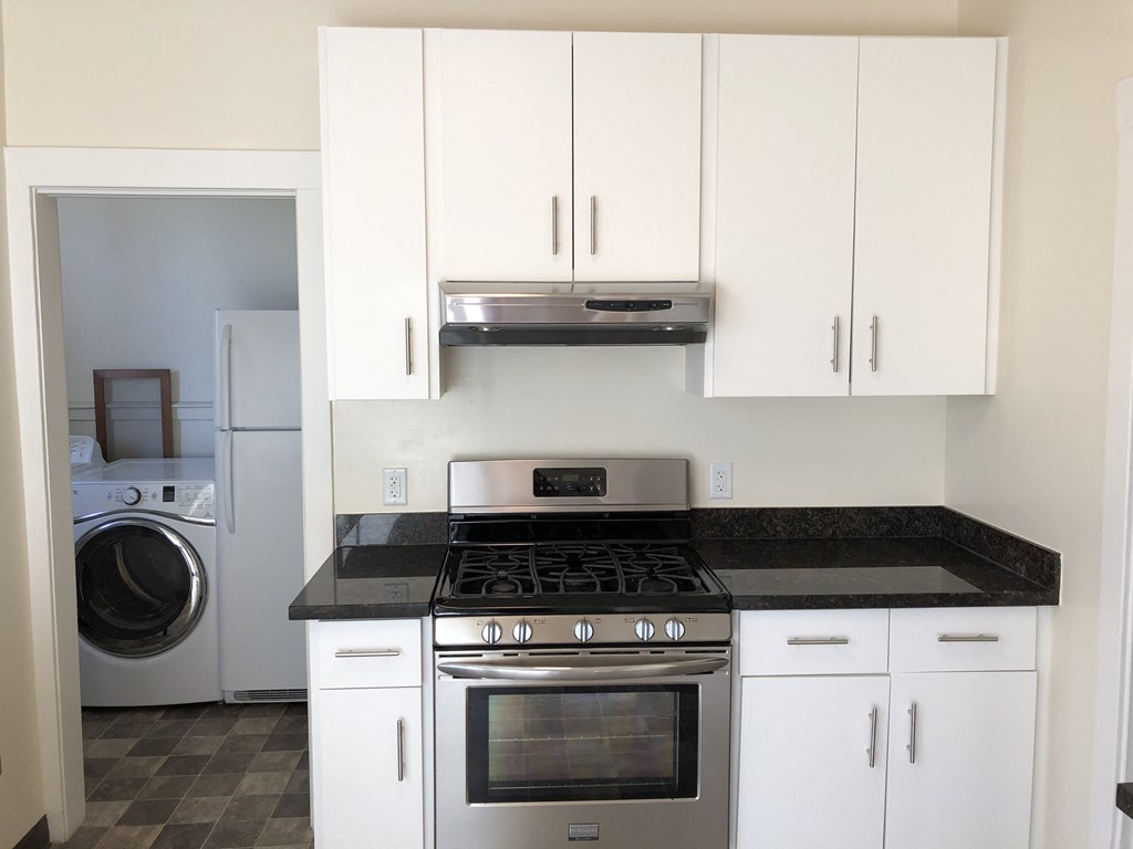 a kitchen with white cabinets and stainless steel appliances and a washing machine