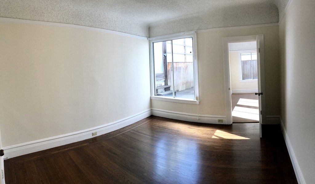 an empty living room with wood floors and a window