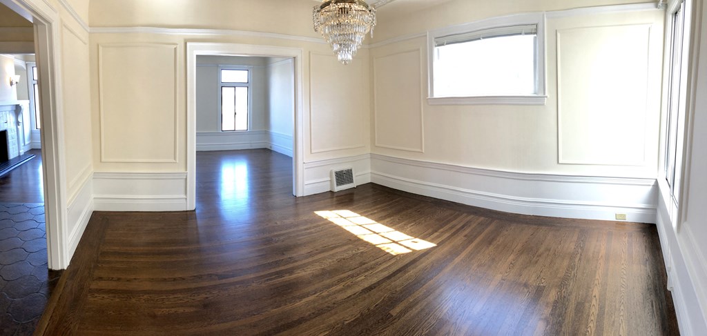 an empty living room with wood floors and a chandelier