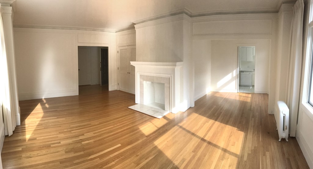 an empty living room with a fireplace and wooden floors