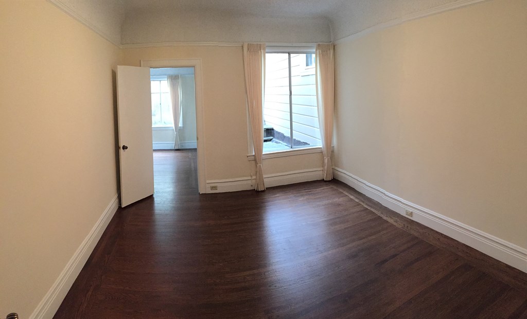 an empty living room with wood floors and a window
