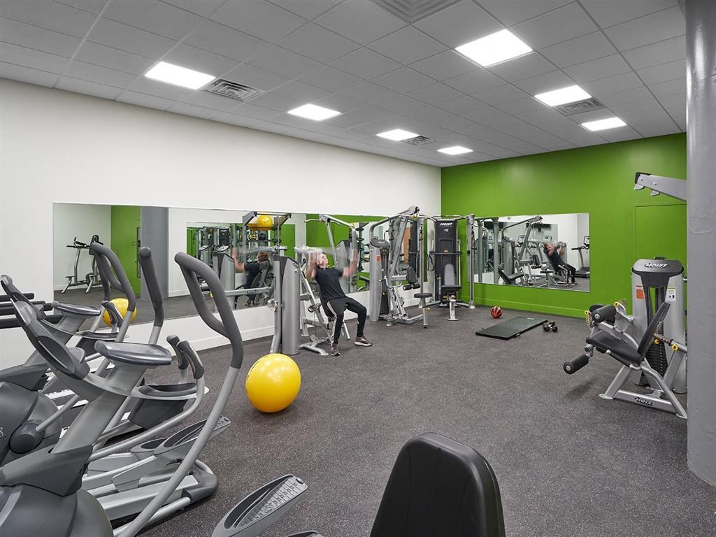 a woman working out in a gym with weights and cardio equipment