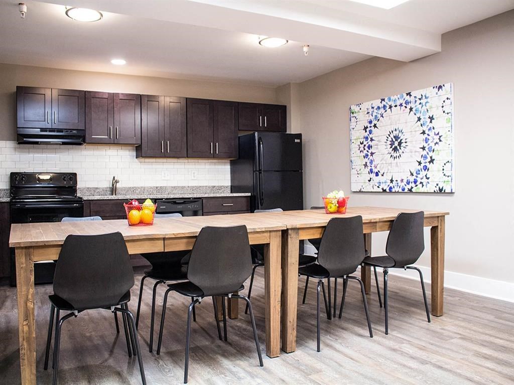 a kitchen with black appliances and a large table with chairs