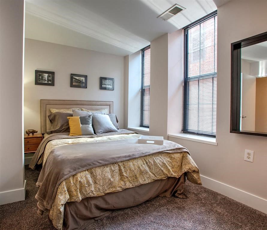 a bedroom with a bed and two windows