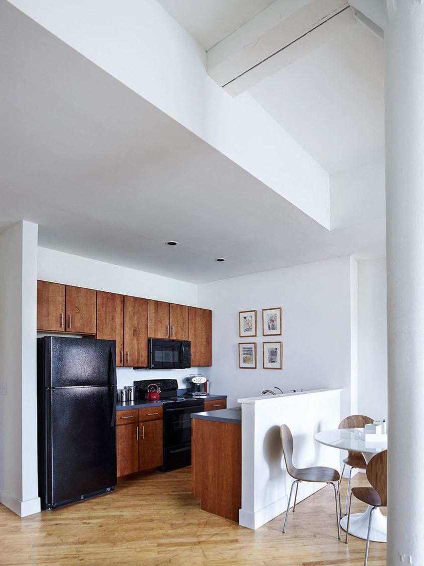 a kitchen with a black refrigerator and a table and chairs