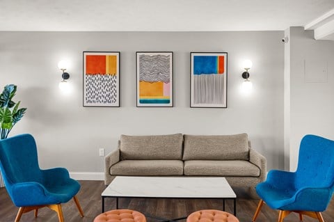a living room with a couch and chairs and paintings on the wall