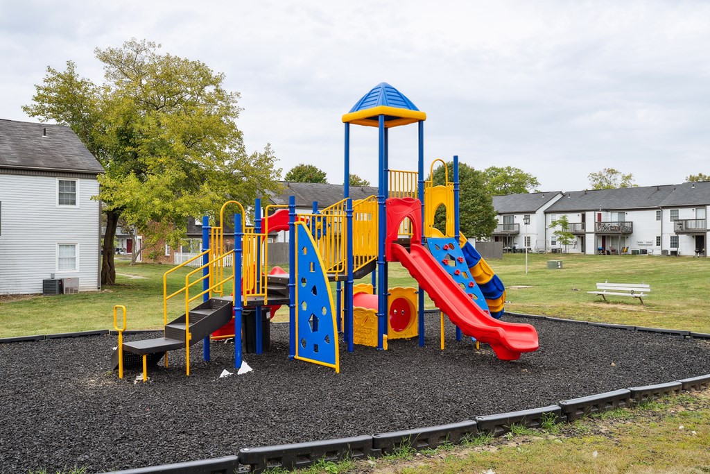 A playground with a red slide and a blue and yellow structure.