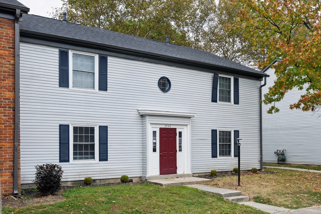A house with a red door and a grey siding.