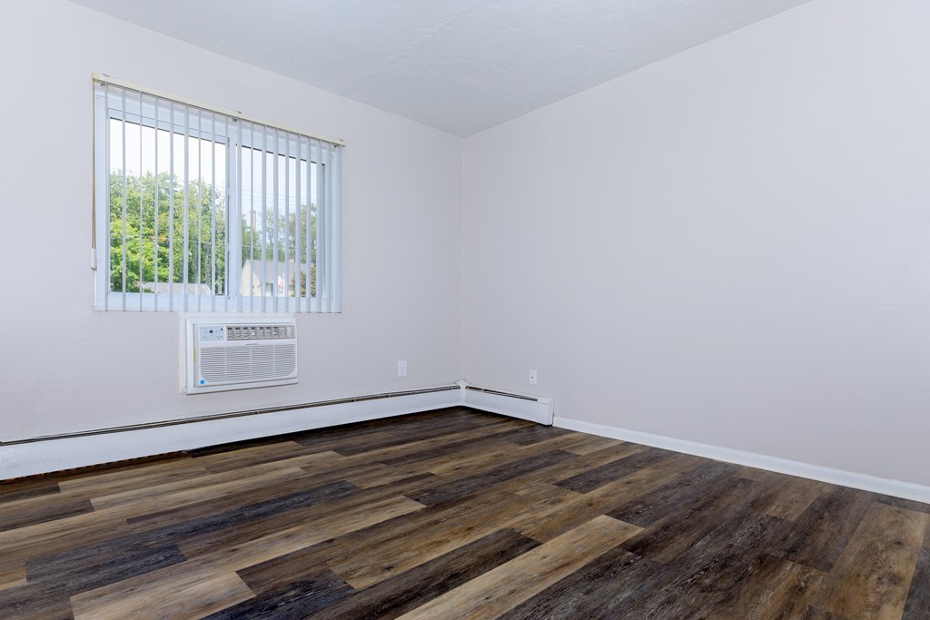 a bedroom with hardwood floors and white walls
