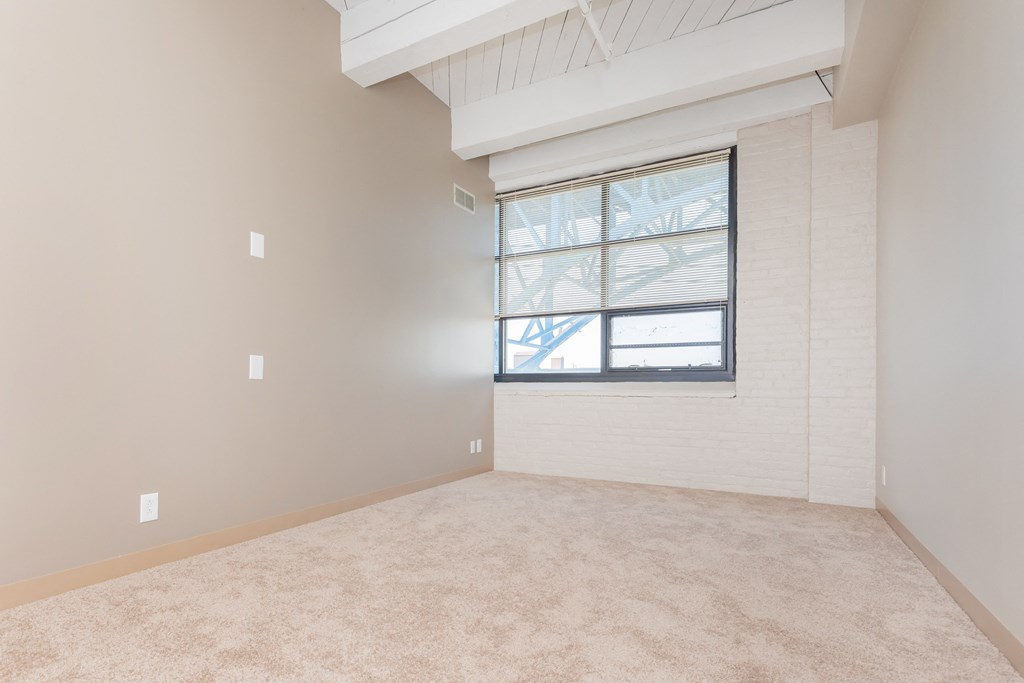an empty living room with a window and carpet