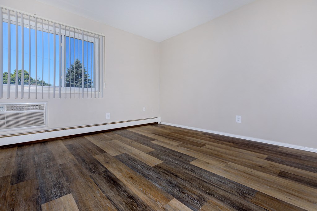 a bedroom with hardwood floors and white walls