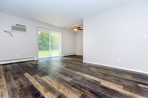 an empty living room with wood flooring and a ceiling fan