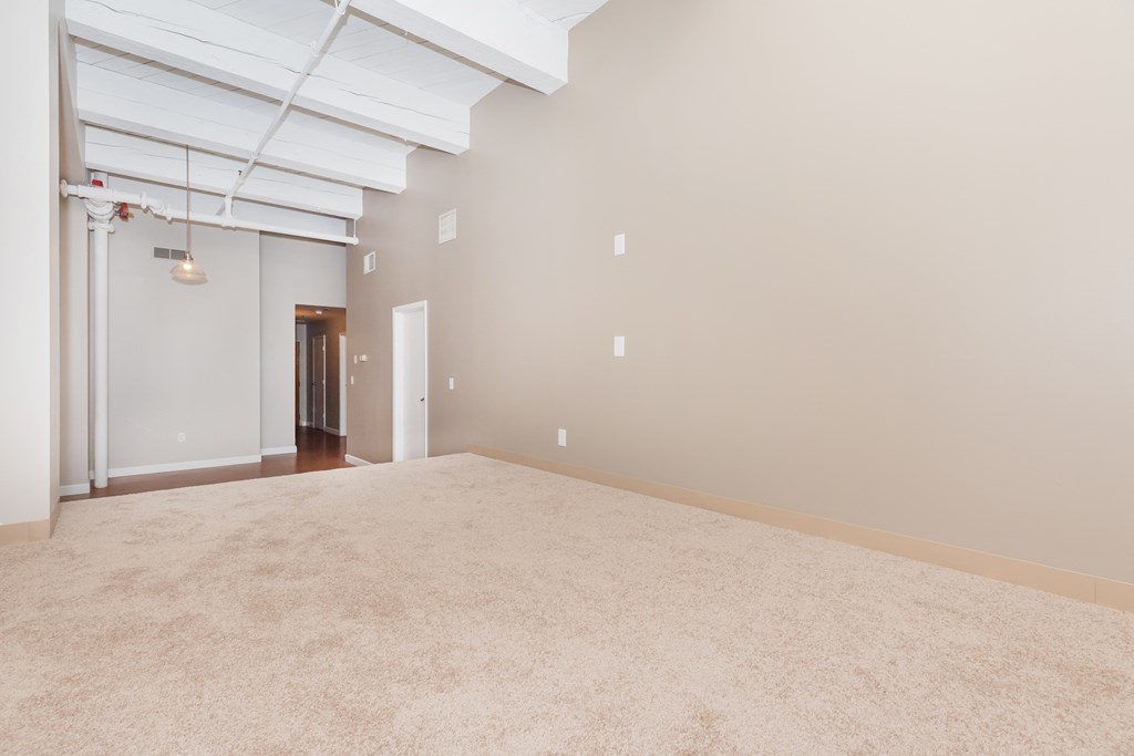 an empty living room with a beige carpet and white walls