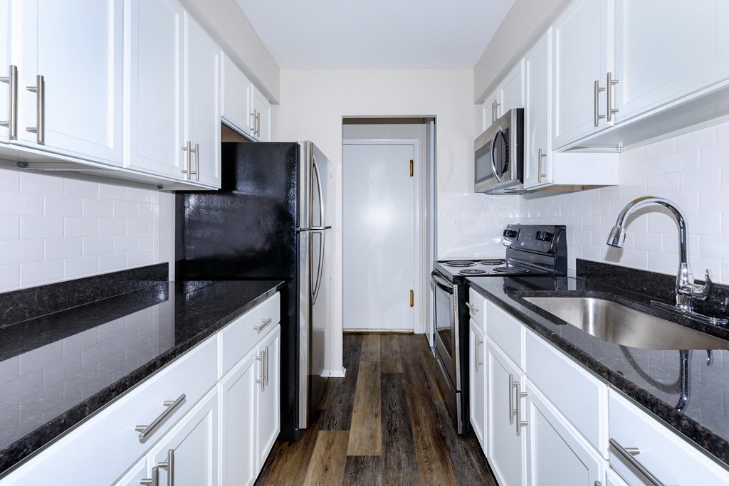 a kitchen with white cabinets and black countertops