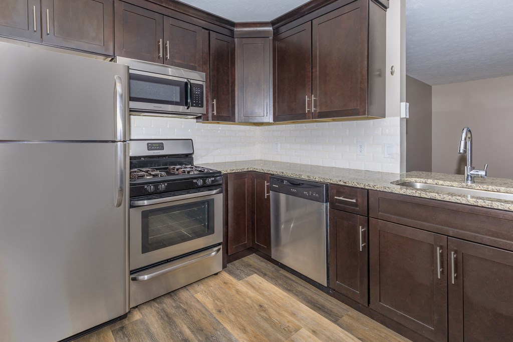 a kitchen with dark wood cabinets and stainless steel appliances