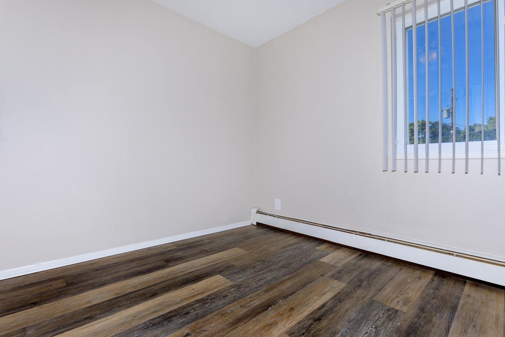 a bedroom with hardwood floors and white walls