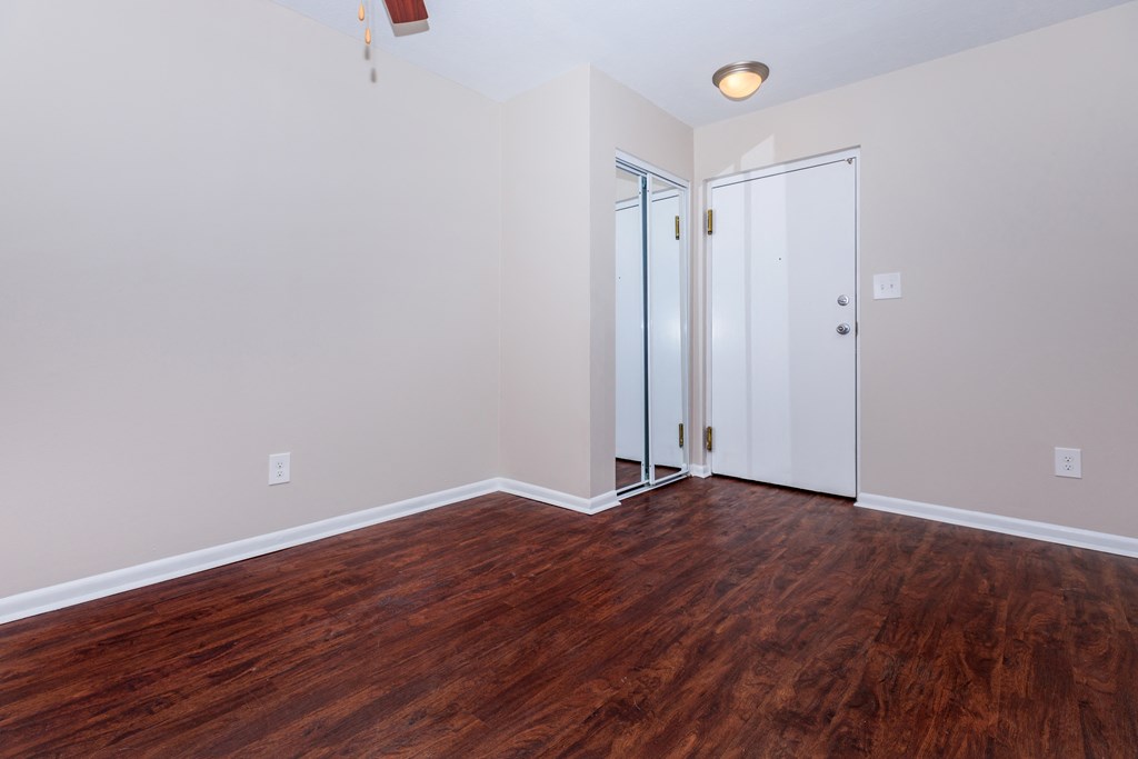 a bedroom with hardwood floors and white walls