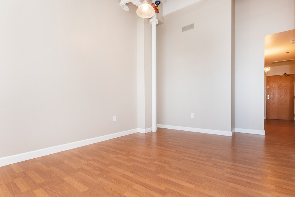 an empty living room with wood floors and white walls