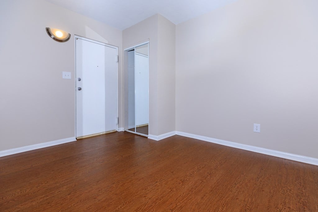 a bedroom with hardwood floors and white walls