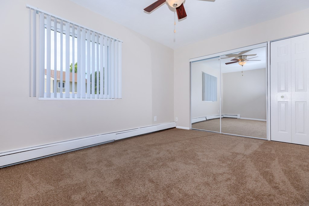 a bedroom with carpeting and a ceiling fan