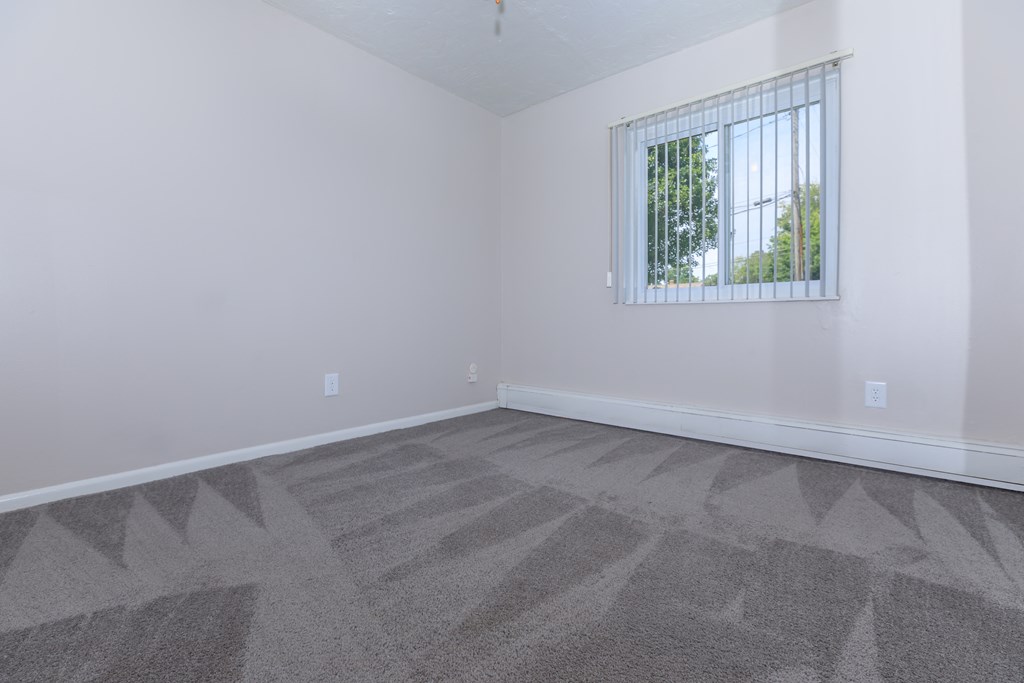 a bedroom with gray carpet and a window