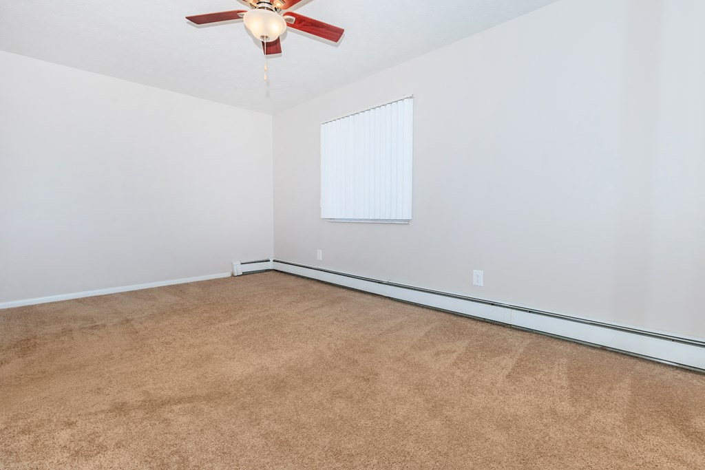 a bedroom with white walls and a ceiling fan