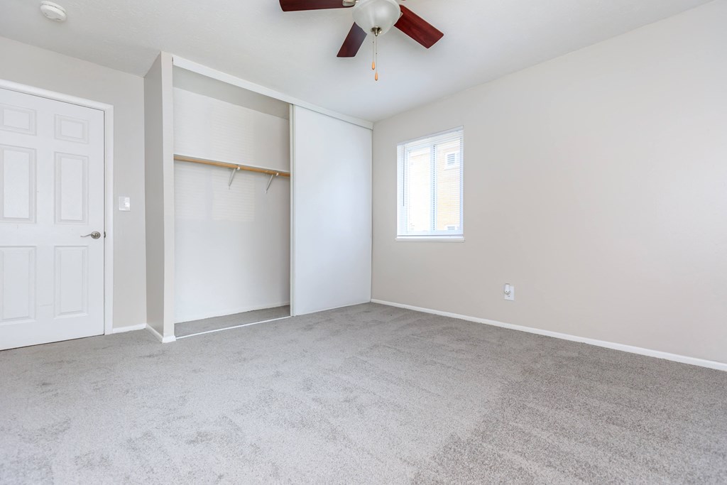 a bedroom with a ceiling fan and a closet