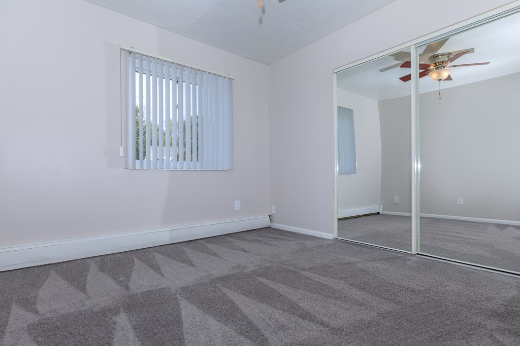 a bedroom with a mirror and a ceiling fan