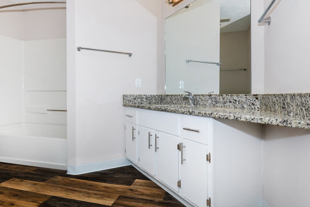 a bathroom with white cabinets and a wooden floor