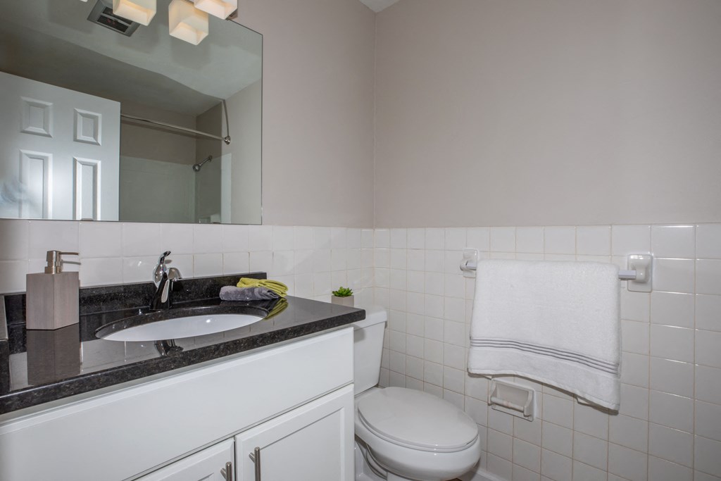 a bathroom with a white toilet next to a sink with a mirror above it