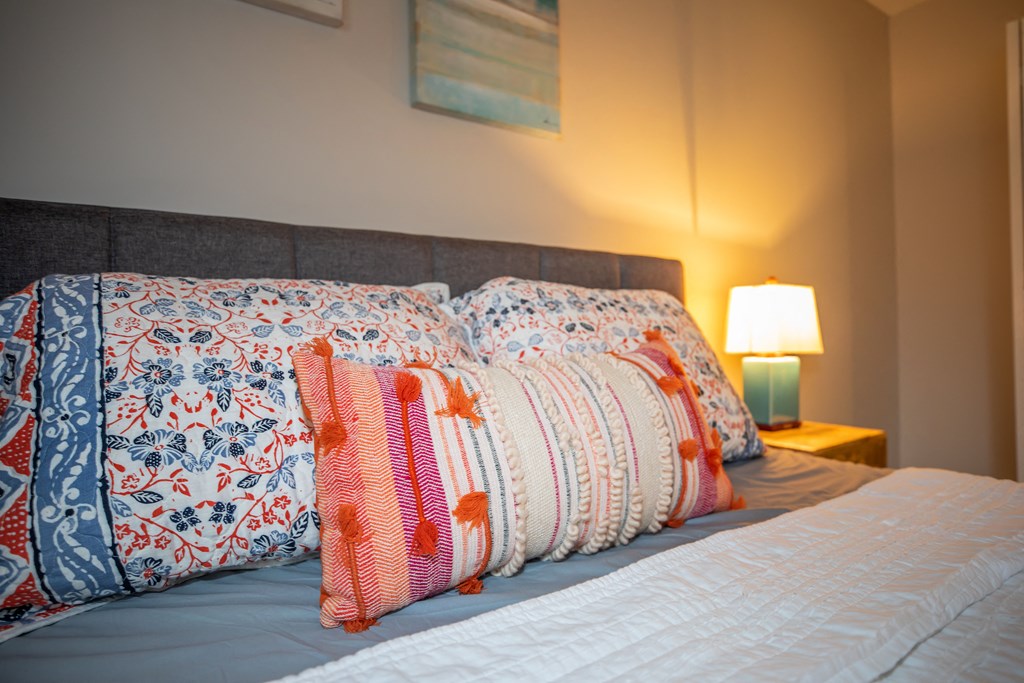 a bed with colorful pillows and a nightstand with a lamp
