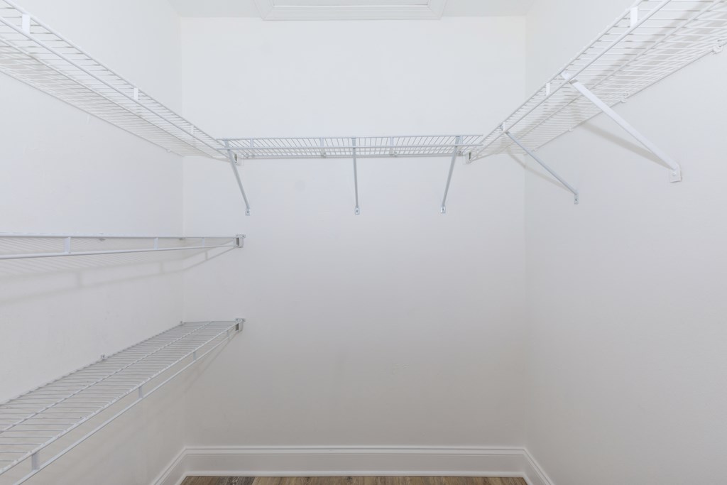 a walk in closet with white walls and white shelves