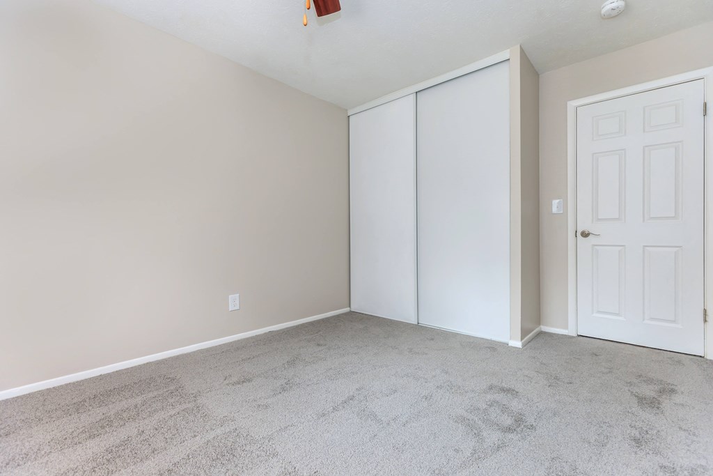 a bedroom with a carpeted floor and a white door