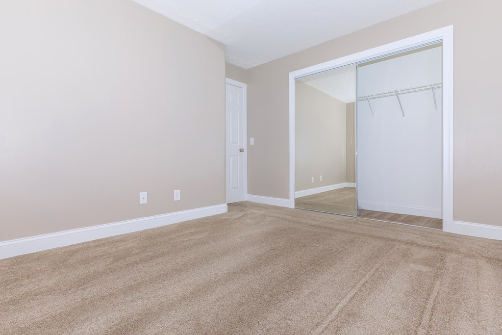 an empty bedroom with a closet and a mirror