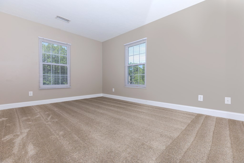 a bedroom with a carpeted floor and three windows