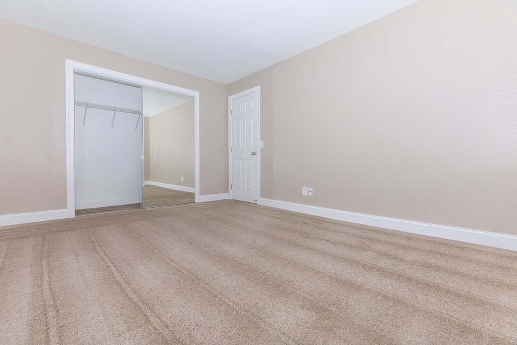 a bedroom with a door to a closet and a carpeted floor