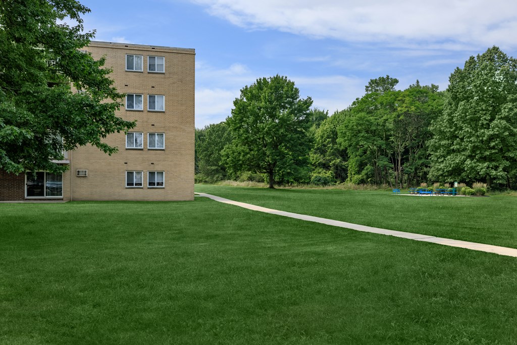 a brick building with green grass and trees in the background