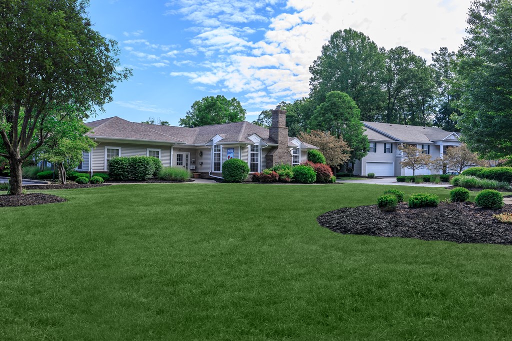 a lush green lawn with two houses in the background