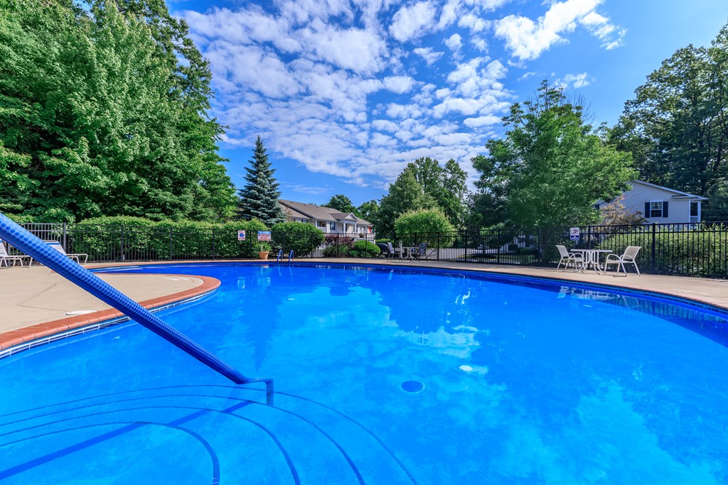a large blue pool with a slide and trees in the background