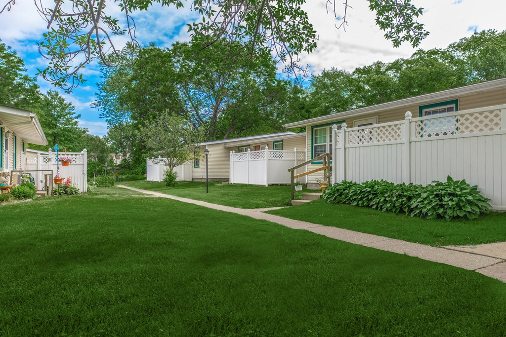 a home with a green lawn and white fence