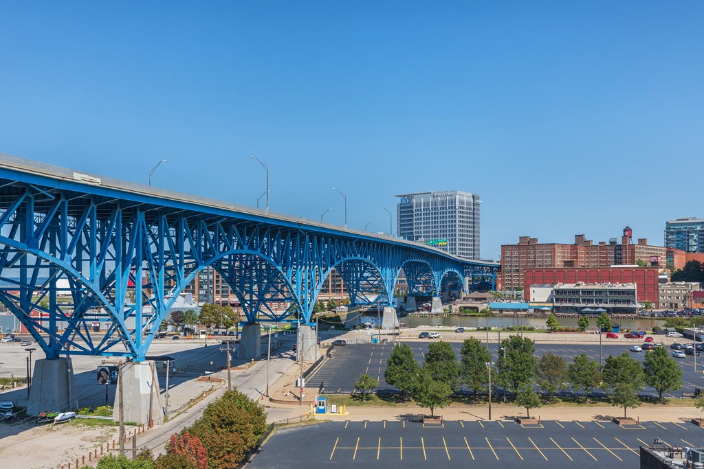 a bridge over a parking lot with a city in the background