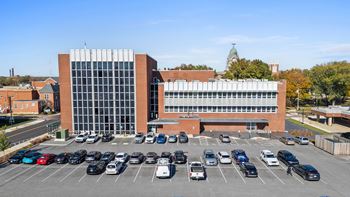 A parking lot in front of a large building with a glass facade.