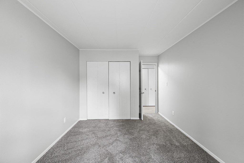 a empty room with carpet and white closets