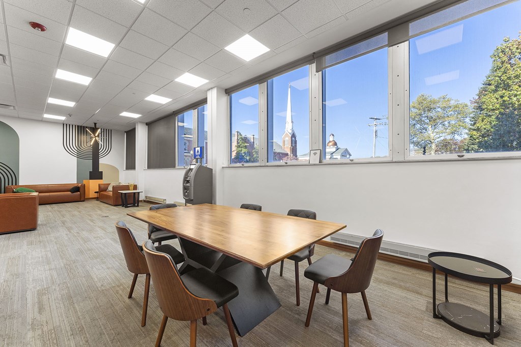 A conference room with a long table and chairs, a sofa, and a view of the city through the windows.