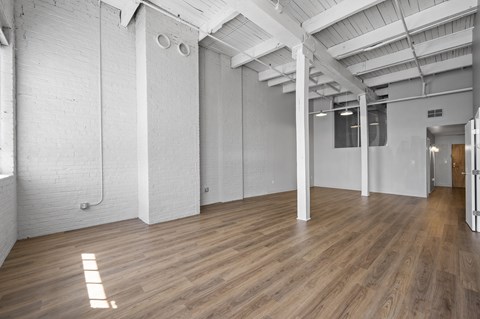 A spacious room with wooden floors and white walls.