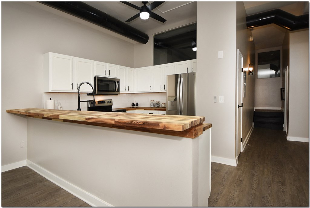 a kitchen with white cabinets and a wooden counter top