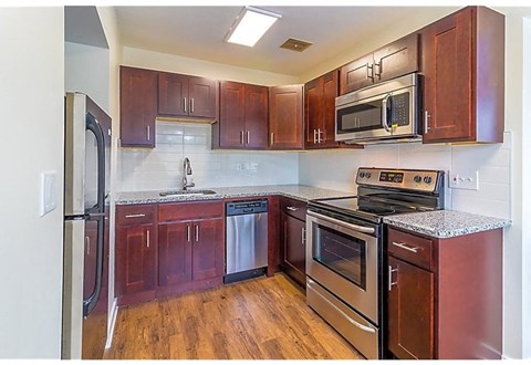 A kitchen with dark wood cabinets and stainless steel appliances.