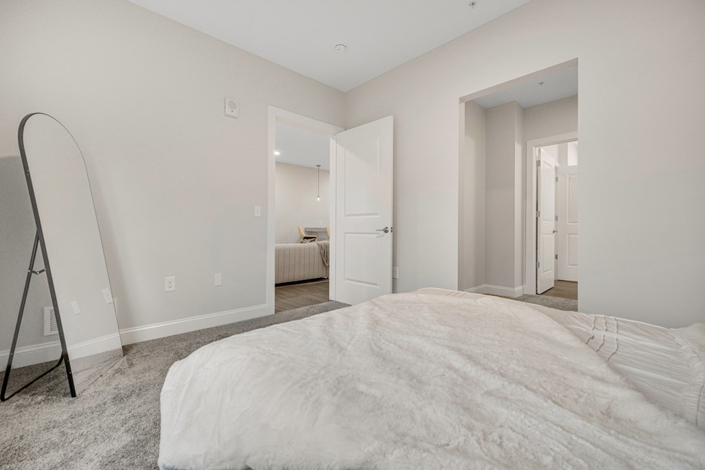 A bedroom with a large bed and a white carpet. at Park Lamont Townhomes Apartments, Cleveland, OH
